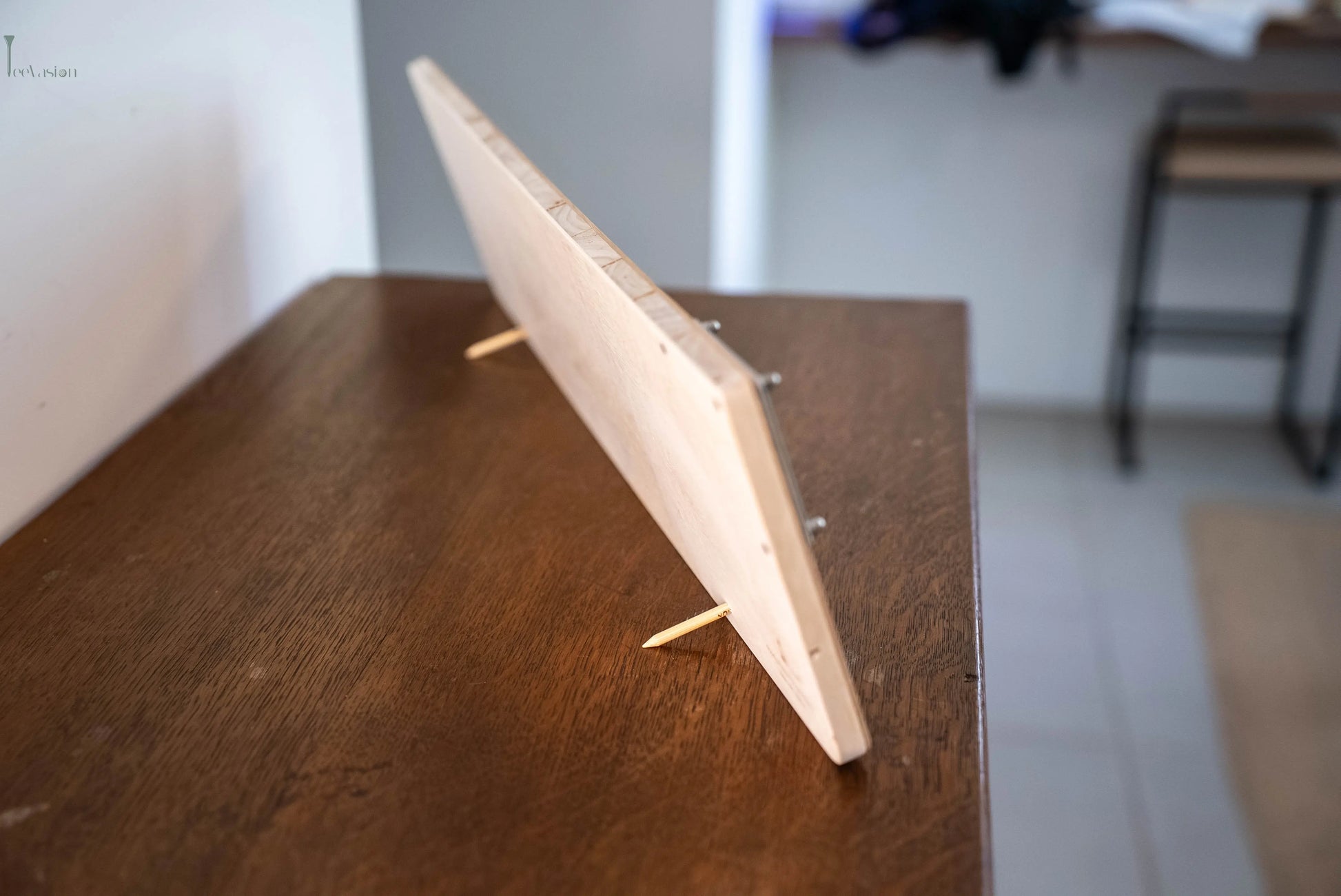 Un grand support de marques balles posé sur un meuble en bois avec ses 2 tees vue de coté