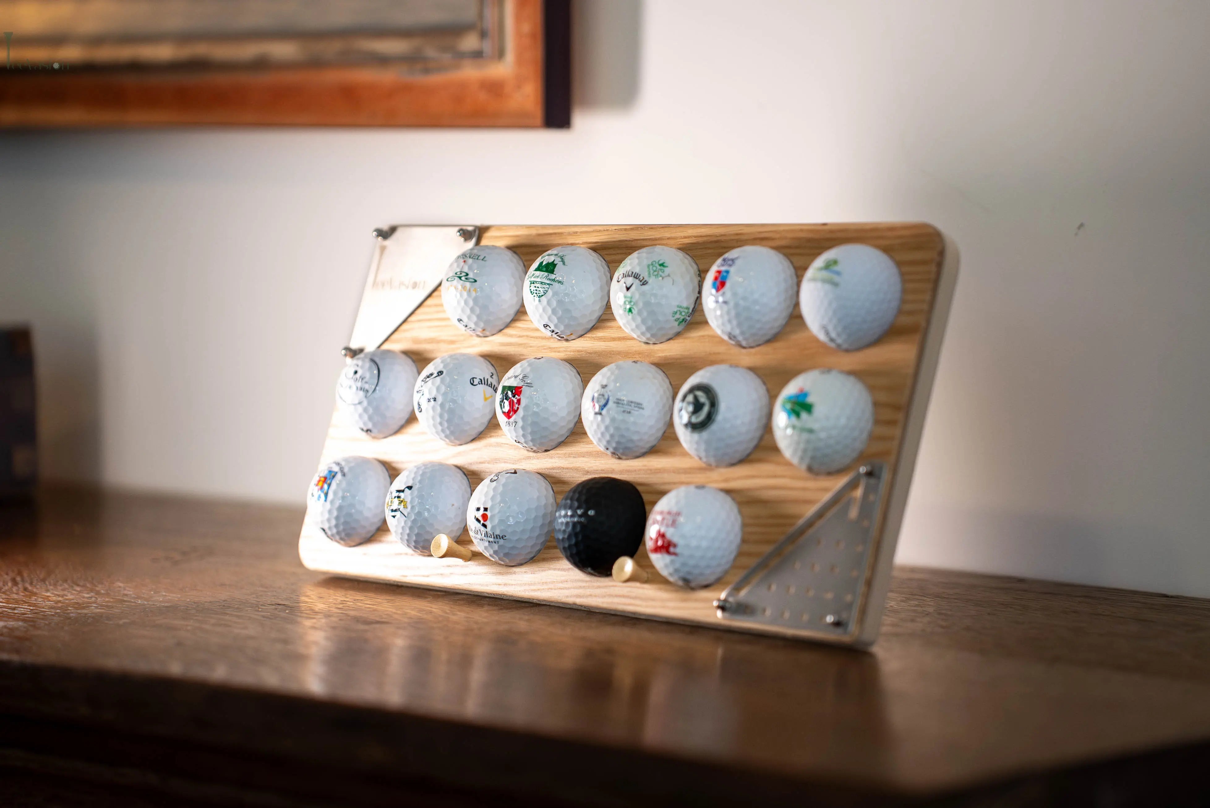 Un support 16 balles avec plaque gravure standard pose sur un meuble en bois avec ses 2 tees