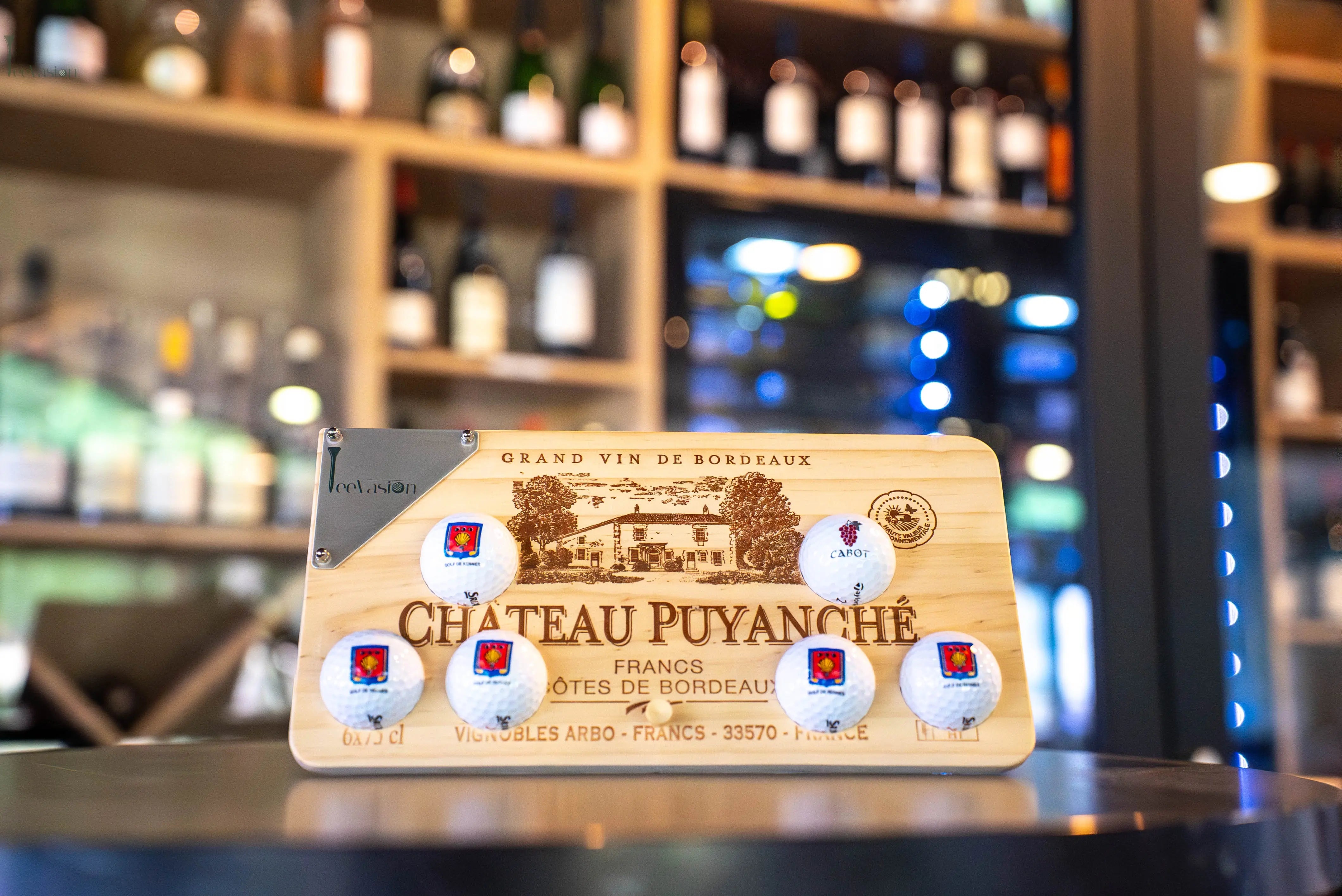 Un support 6 balles sur caisse de vin avec plaque gravure classique pose sur son tee dans la cave d'un restaurant