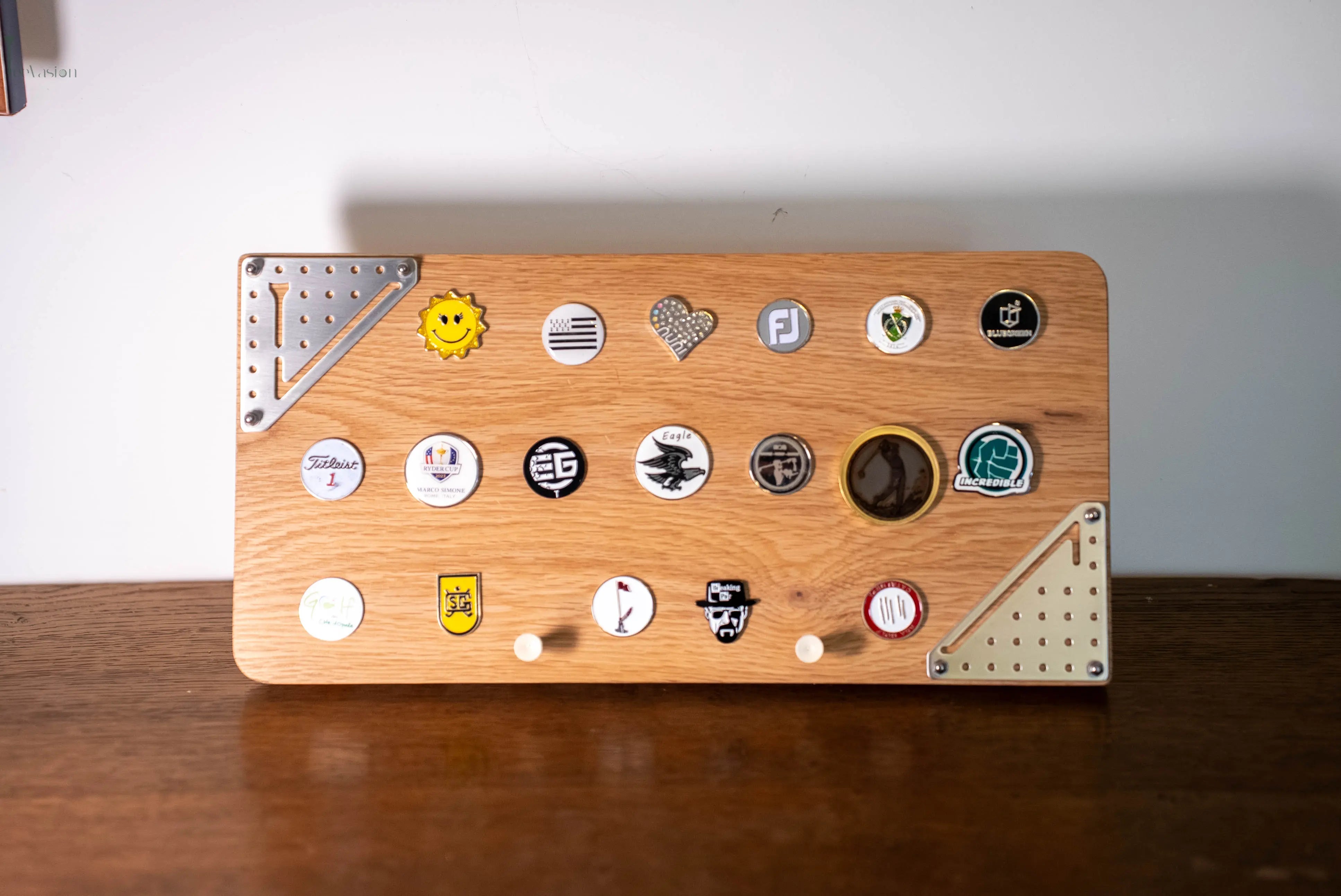 Un support de marques balles taille moyenne posé sur un  meuble en bois avec ses 2 tees et la plaque classique teevasion